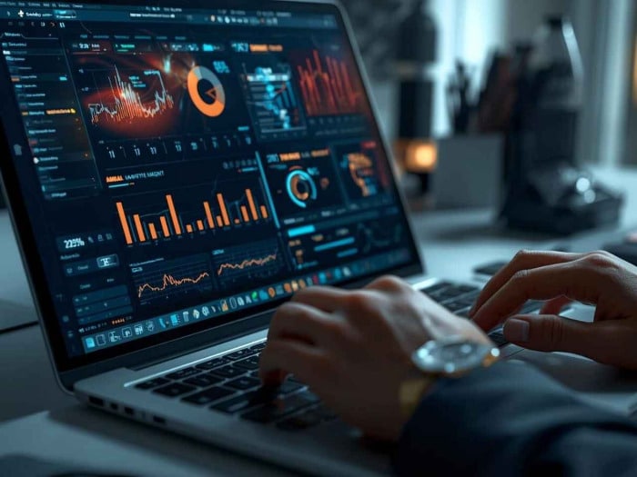 a person types on a laptop displaying data analytics dashboards graphs and charts in orange and blue tones indicate financial insights, suggesting focus
